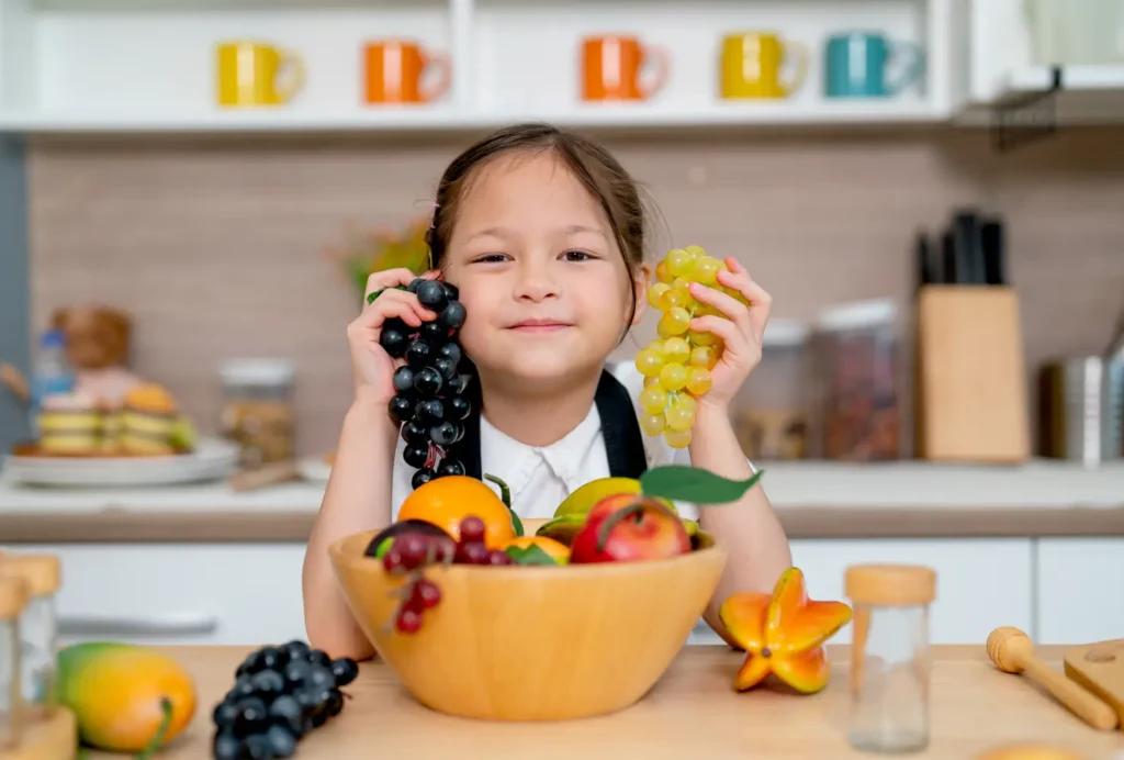 Clínica del Crecimiento | Niño comiendo frutas frescas con sonrisa - prevenir la obesidad infantil- clinica del crecimiento