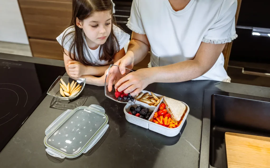 Padres preparando juntos una lonchera saludable niños en casa- clinica del crecimiento