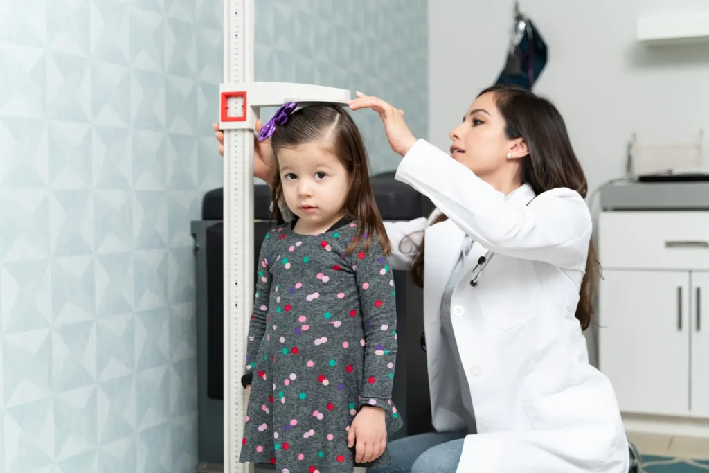 Médico pediatra mostrando una tabla de peso y estatura a los padres- clinica del Crecimiento