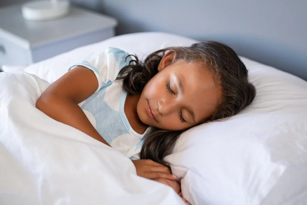 Niño dormido plácidamente en su cama – beneficios de dormir bien en los niños - clinica del crecimiento